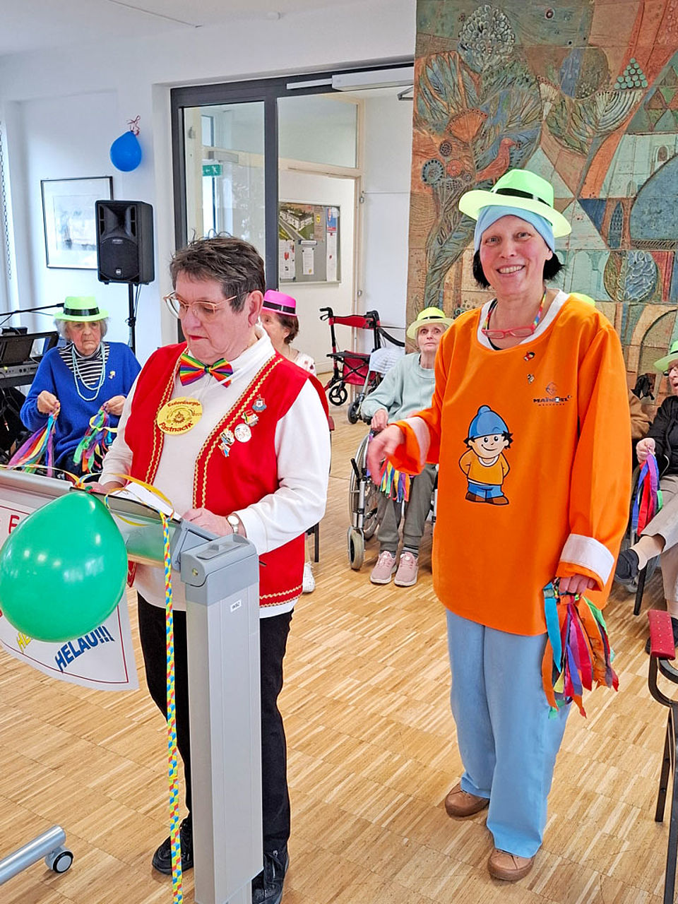 Zwei verkleidete Damen stehen an einem Rednerpult und halten eine Fastnachtsrede