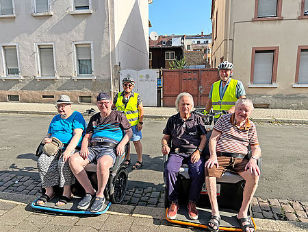 Seniorinnen und Senioren werden mit der Rikscha kutschiert