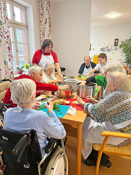 Senioren und Seniorinnen sitzen gemütlich zusammen zum Frikadellen essen