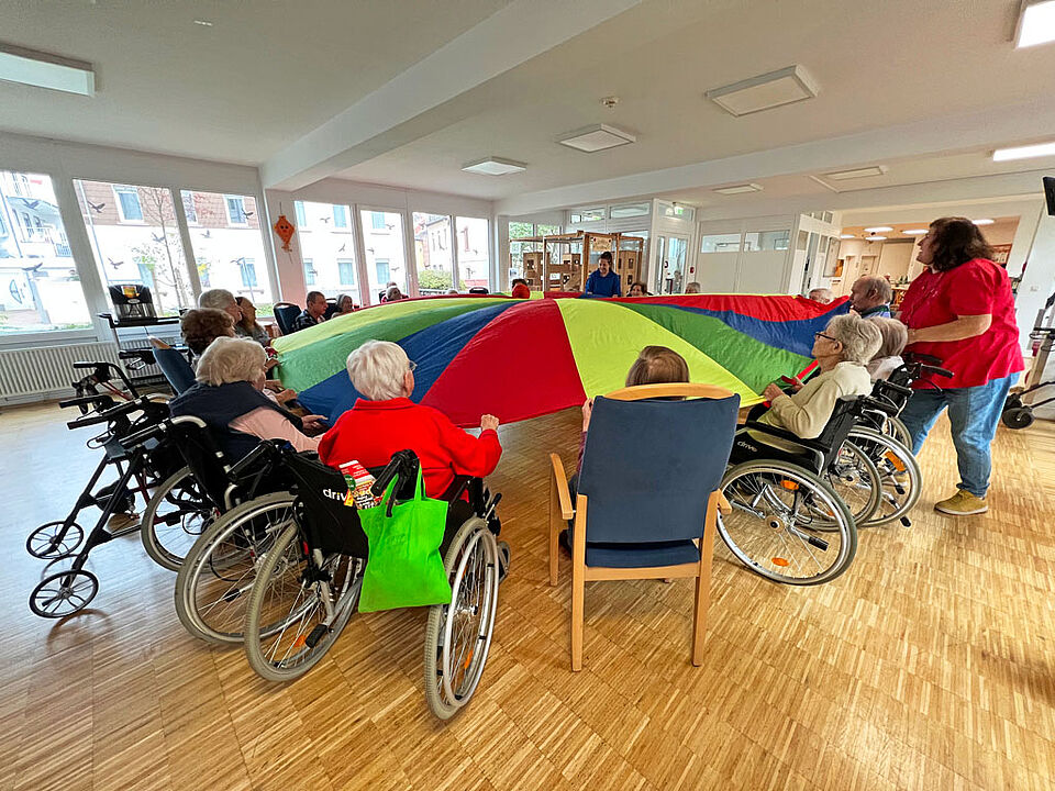 Herbst Angebote Schwungtuch Im Herbst-Angebot arbeiten die SeniorInnen im Kreis sitzend mit einem farbenfrohen Schwungtuch