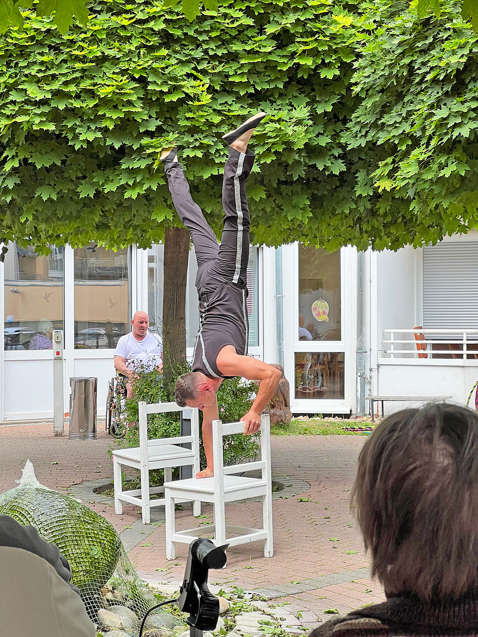 Ein Akrobat macht einen Handstand auf einem Stuhl