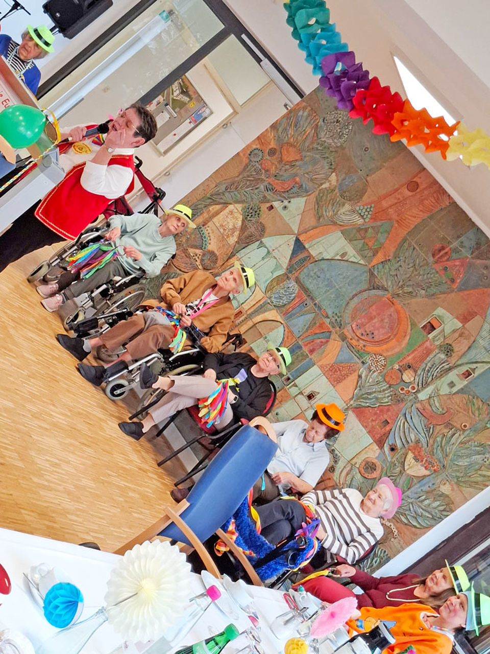 Senioren sitzen verkleidet zusammen und hören einer Fastnachtsrede zu