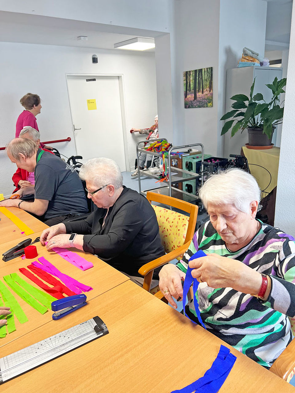 Bunte Bänder basteln Seniorinnen und Senioren sitzen zusammen und basteln bunte Bänder