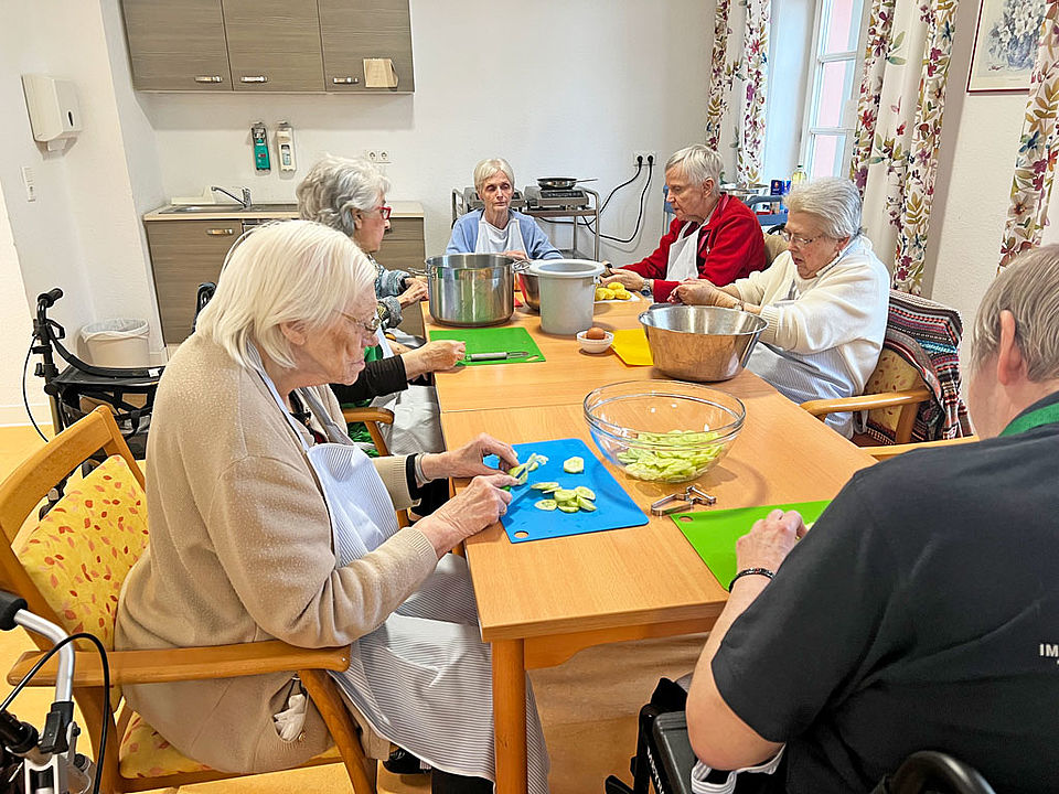 Senioren und Seniorinnen sitzen gemütlich zusammen zum Frikadellen essen