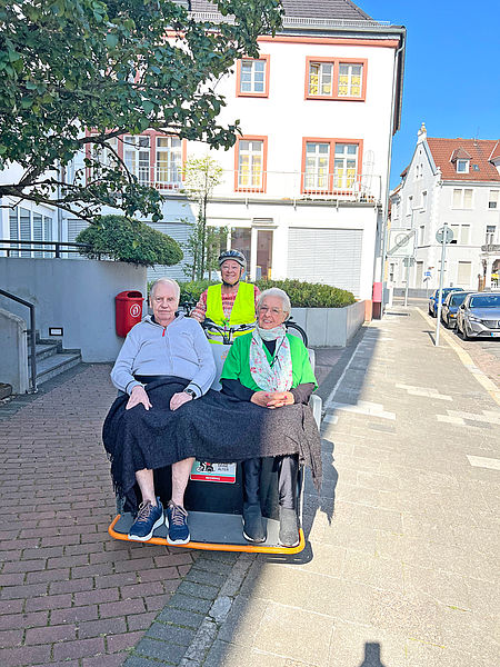 Ein Rentner und eine Rentnerin werden auf der Rikscha gefahren