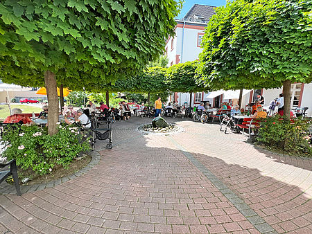 Seniorinnen und Senioren essen im Garten Kartoffelpfannkuchen und hören dabei Musik