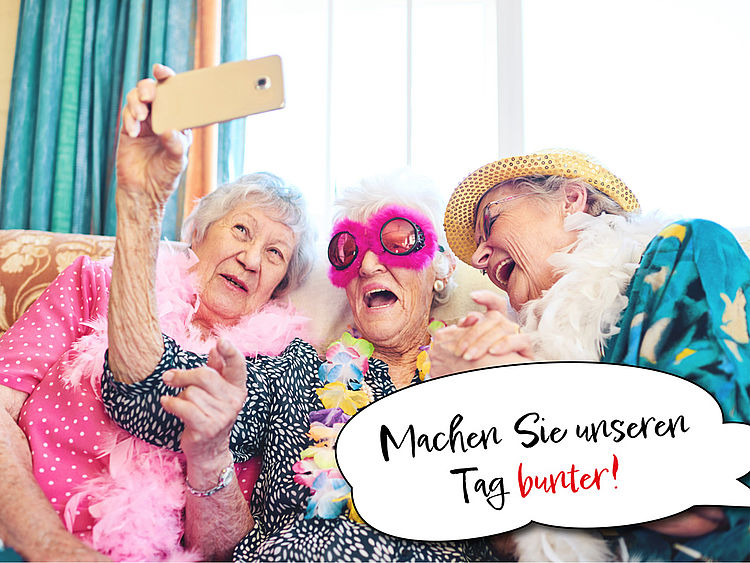 Drei Seniorinnen sind bunt verkleidet und lachen darüber