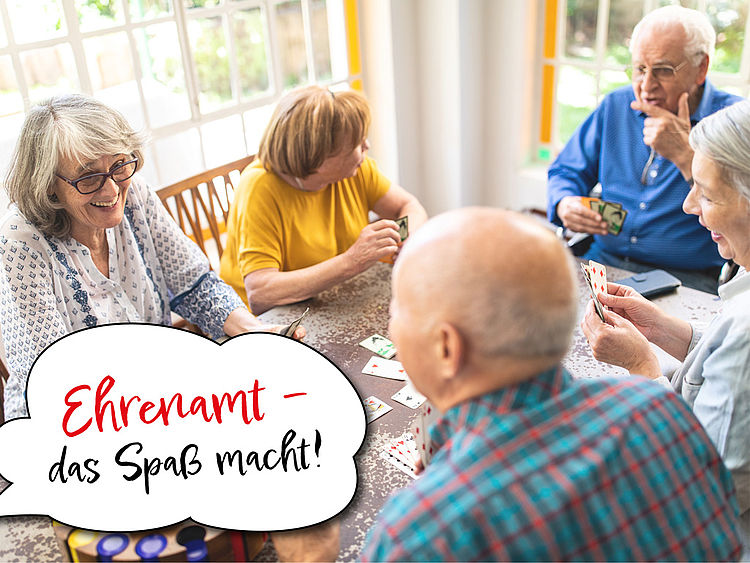 Mehrere Senioren sitzen bei einem Kartenspiel zusammen und haben Spaß