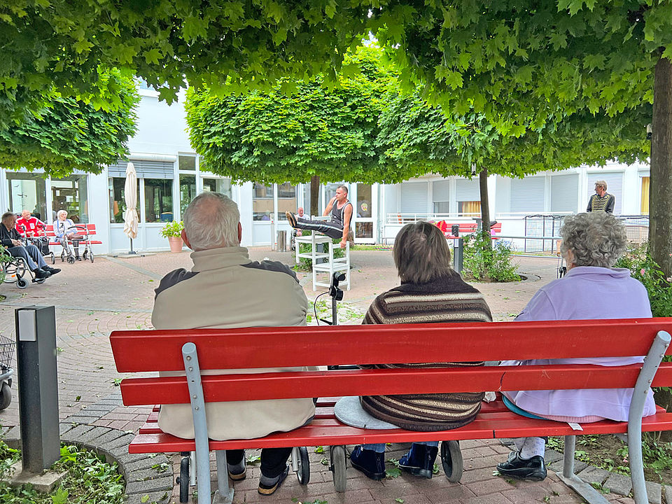 Senioren beobachten einen Akrobaten der auf Stühlen turnt