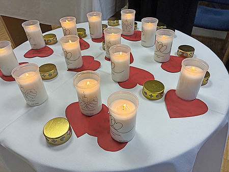 ausgeschnittene Herzen und brennende Kerzen auf einem Tisch