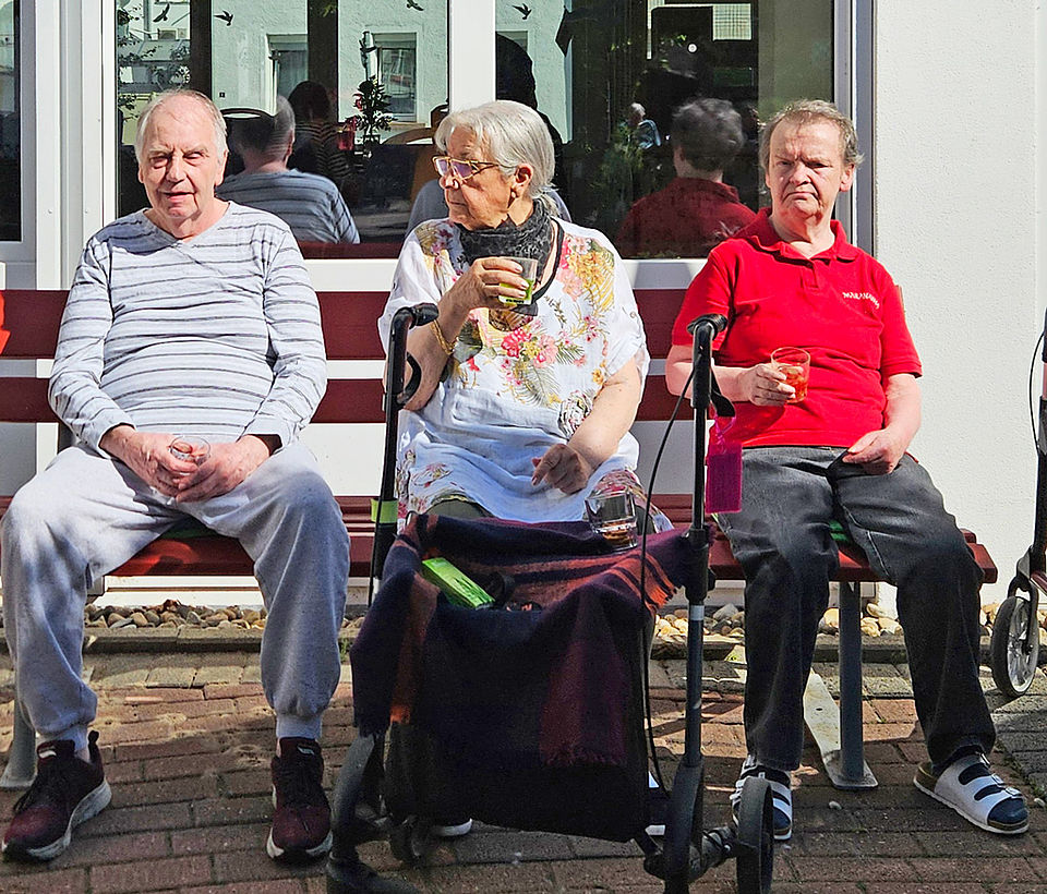 Drei Senioren sitzen auf der Gartenbank