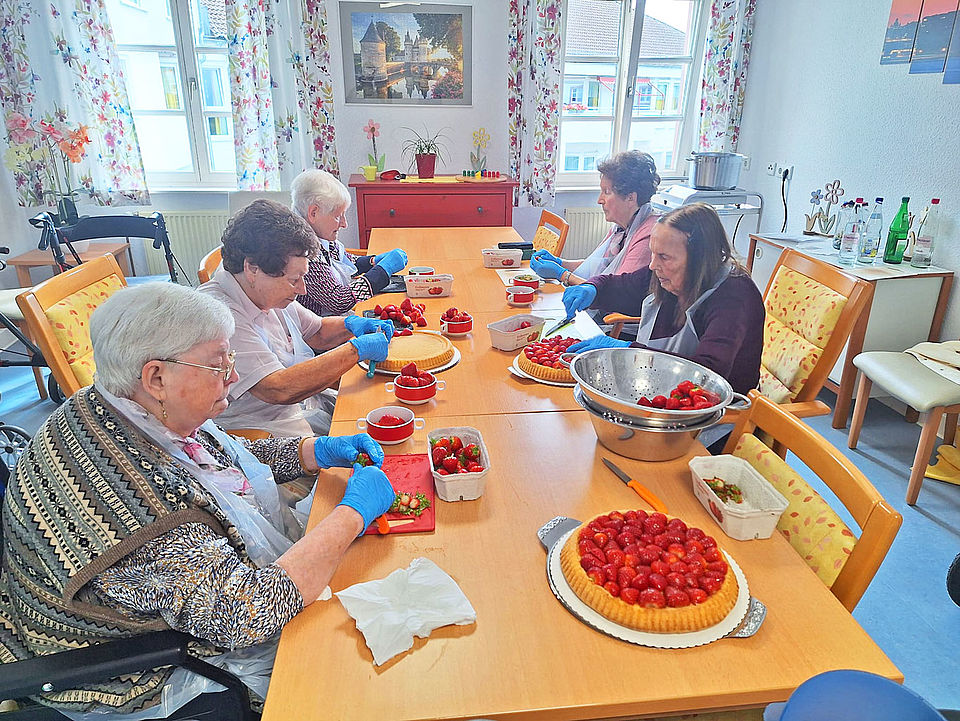 Senioren bereiten zusammen einen Erdbeerkuchen zu