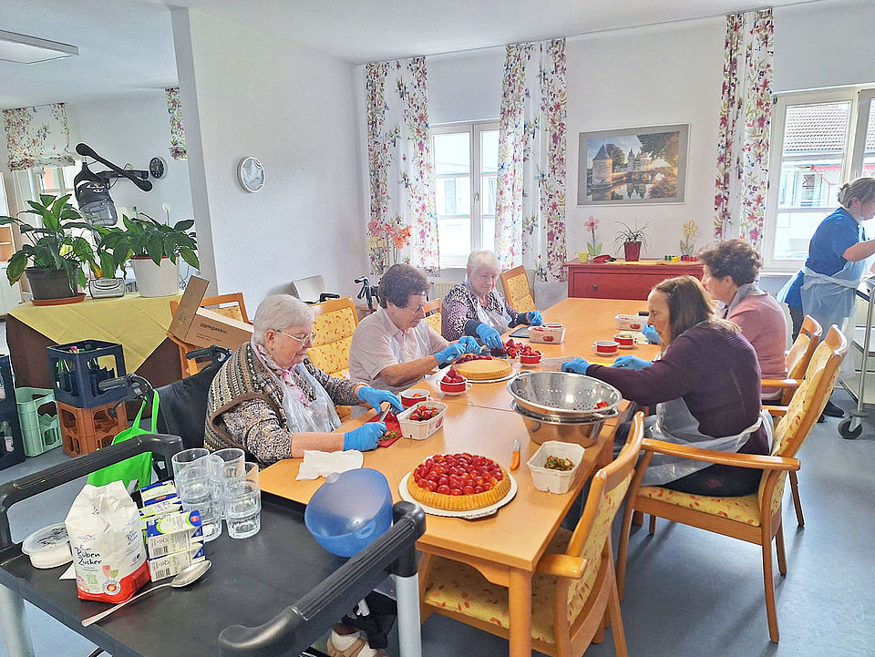 Senioren bereiten zusammen einen Erdbeerkuchen zu