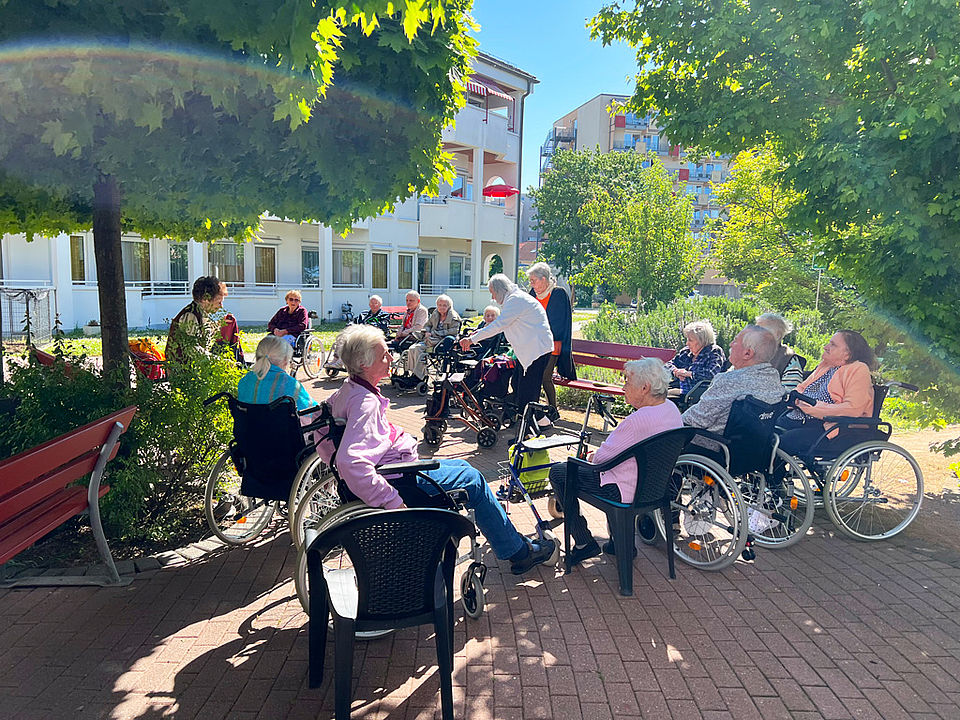 Eine Gruppe von Senioren trifft sich im Garten des Pflegeheims
