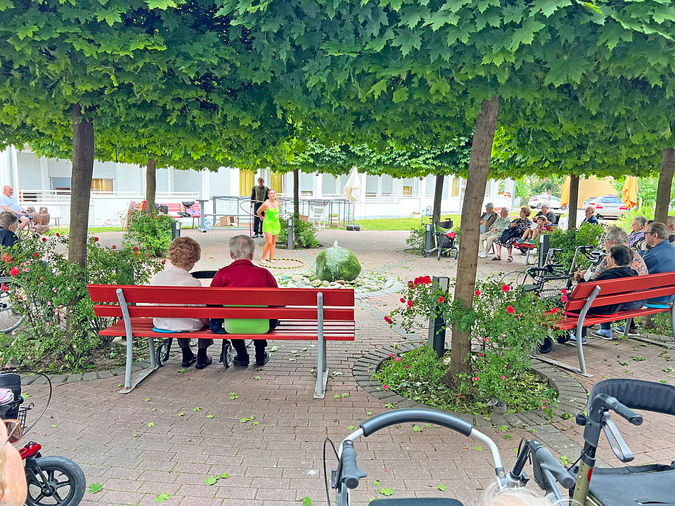 Senioren beobachten eine Hulahoop-Akrobatin