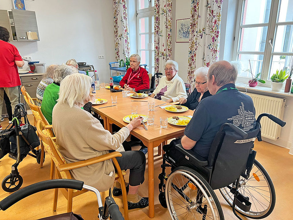 Senioren und Seniorinnen sitzen gemütlich zusammen zum Frikadellen essen