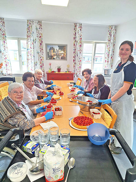 Senioren bereiten zusammen einen Erdbeerkuchen zu