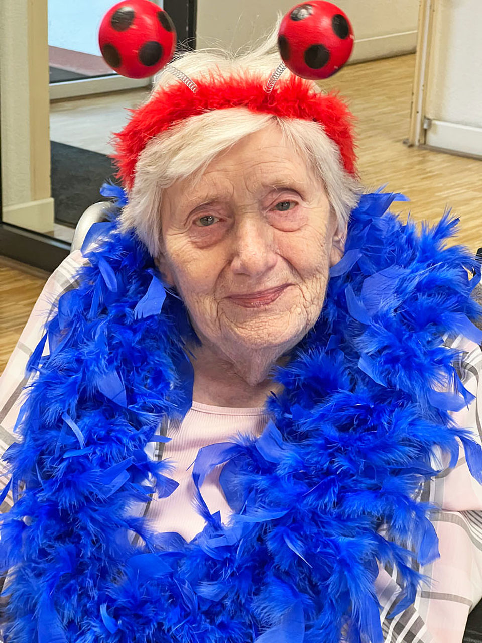 Seniorin verkleidet mit Federschal und Fußballhaarreif