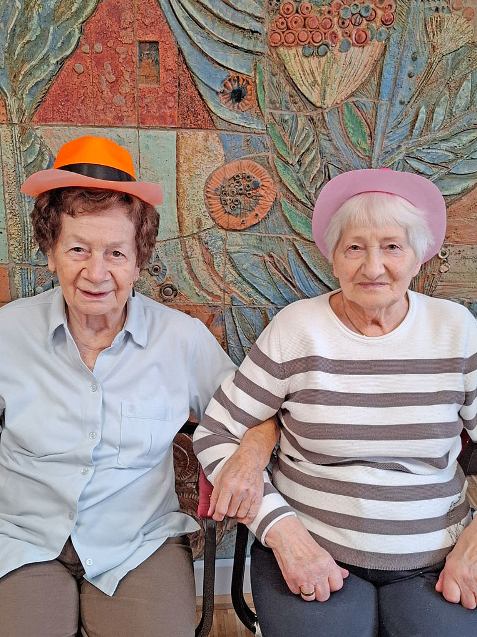 zwei Seniorinnen mit Hut sitzen zusammen