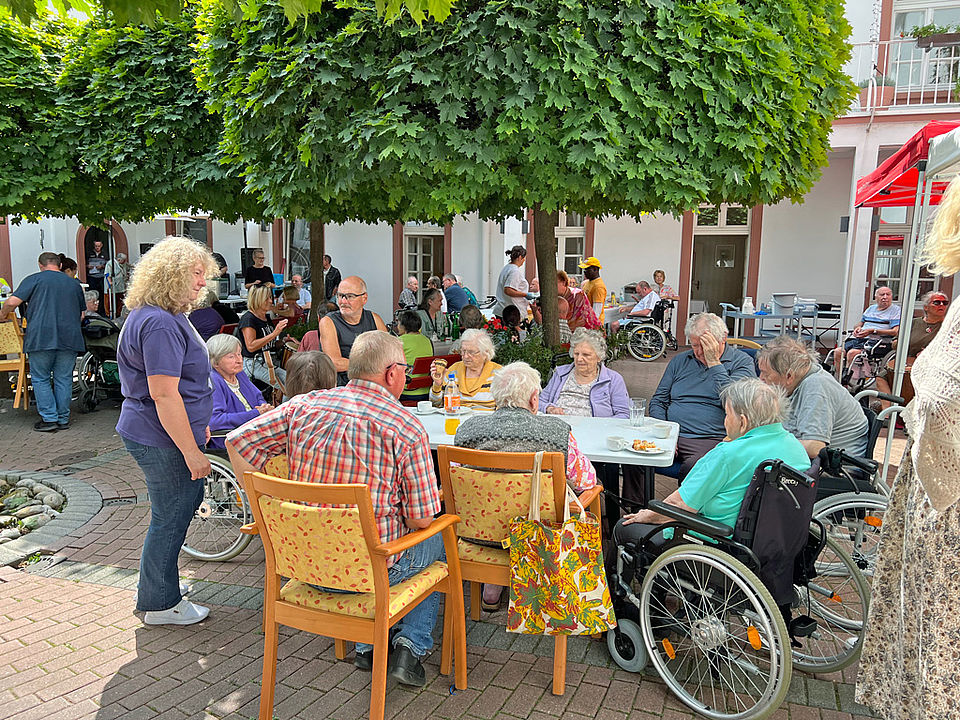 Beim Sommerfest sitzen alle gemütlich im Garten beisammen