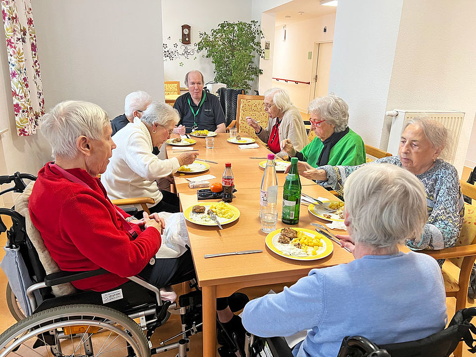 Senioren und Seniorinnen sitzen gemütlich zusammen zum Frikadellen essen