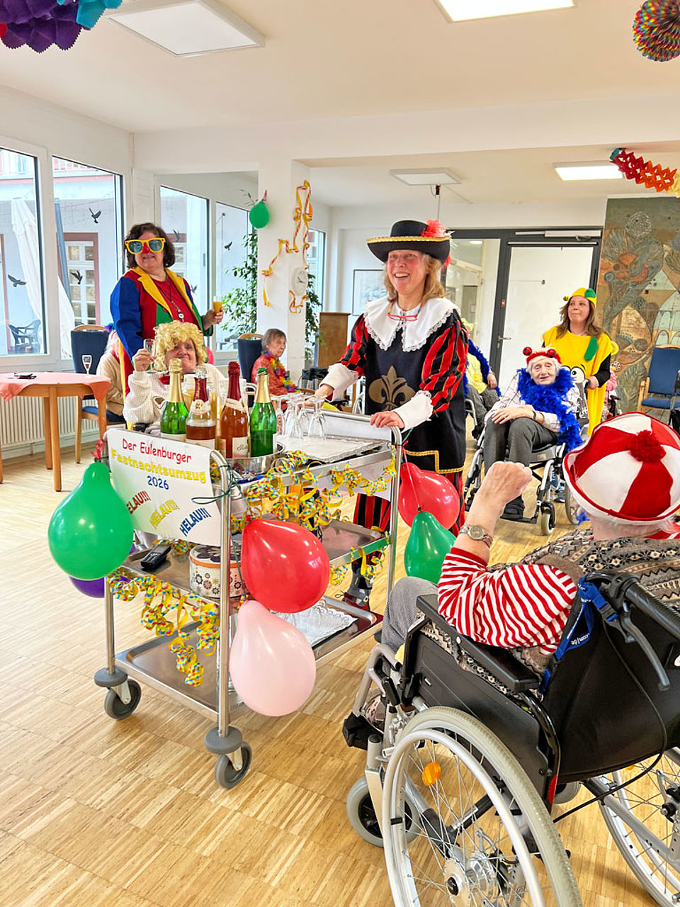 Verkleidete Mitarbeiterinnen reichen Getränke an die BewohnerInnen des Seniorenzentrums