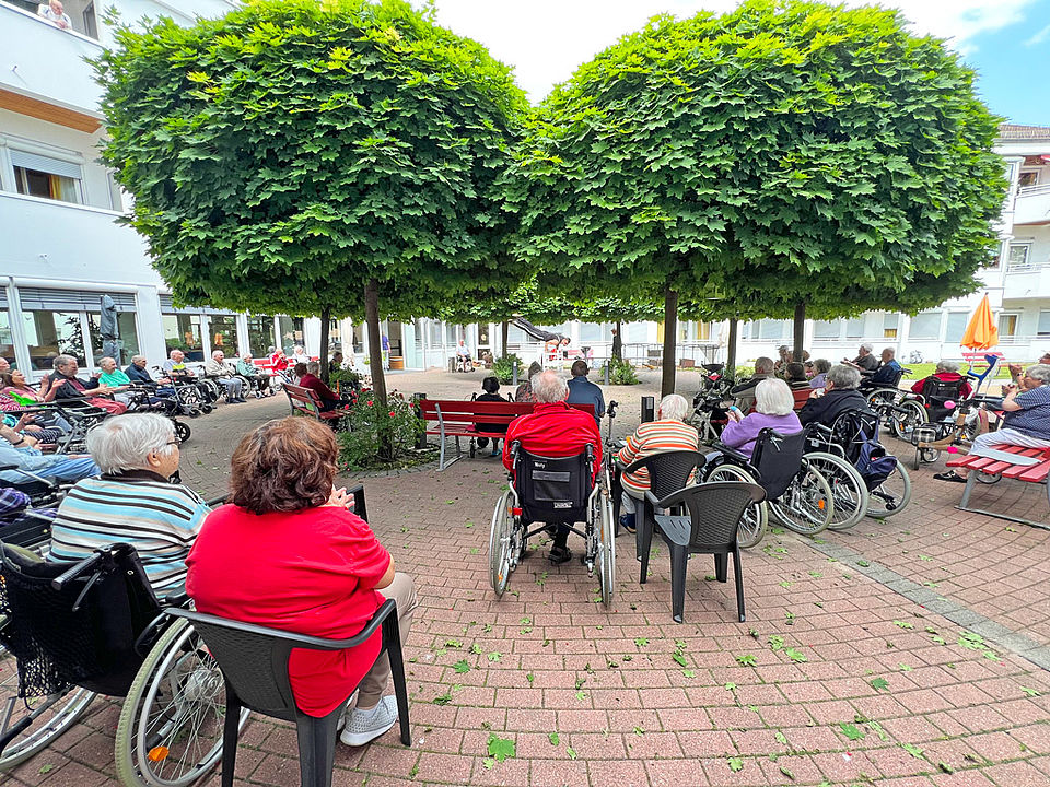 Senioren sitzen im Garten und beobachten einen Akrobaten